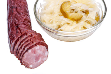 Traditional organic raw and fermented sauerkraut with pickled Persian cucumbers and homemade smoked pork sausage isolated on white background.
