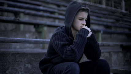 Fototapeta premium Upset boy sitting on stadium tribune, feels depression, loneliness and sorrow