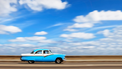 American bright blue retro car on the seafront of the capital of Cuba Havana against the blue sky...