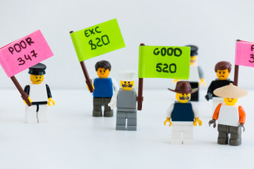 Plastic multicolored little people toy are holding a sign with the inscription credit score, excelent, good, bad. Credit history. Concept. Family and person finance. Bank.