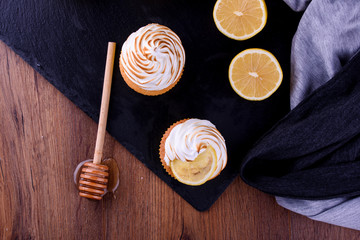 Lemon muffins with protein cream on a slate board with powdered sugar and honey