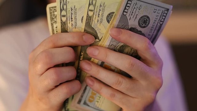 Casual woman is counting american dollar banknotes, close up of hands with money