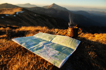 A cup of hot drink and map on the background of mountains