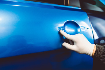 Car wrapping specialist putting vinyl foil or film on car. Selective focus.