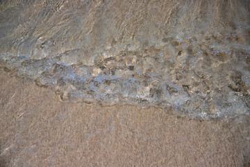 Yellow sand beach with clear sea water tide. Small seawater wave over coral beach. Sunny tropical seaside abstraction.