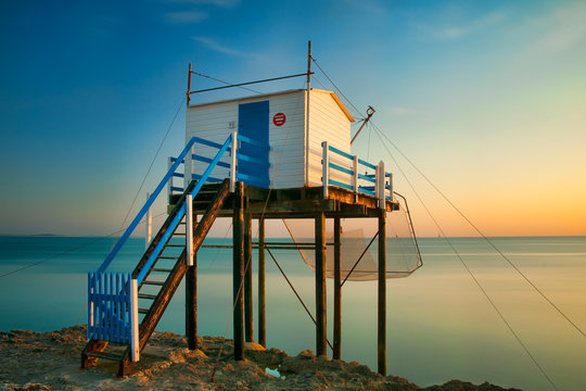 View of fishing cabin by sea during sunset