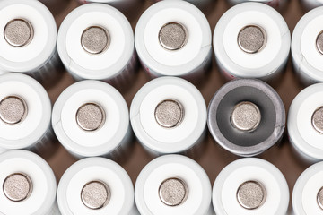 AA batteries are located close to each other. Close-up of all white batteries, except one black, on a white background. Battery technology
