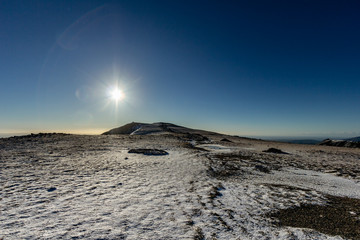 Snowy mountain summit with a majestic blue sky and starry sun