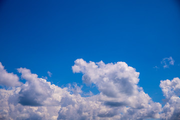 Naklejka na ściany i meble White cloud and clear blue sky above. Sunny cloudscape photo background. Skyscape with fluffy clouds.