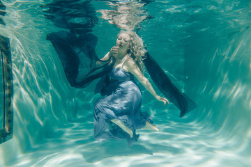 chubby sexy woman in grey evening long dress swimming underwater on her holidays and enjoy with...