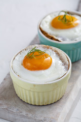 Baked eggs in ramekins close view, selective focus