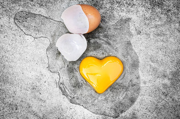 Obraz premium Heart Shape Egg Yolk with eggshells on the ground. Concept Valentines Day