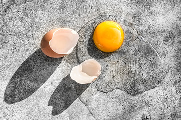 Raw egg with eggshells on the ground.
