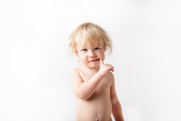 portrait of curly blonde little baby girl on white background. baby sucks his finger. childcare...