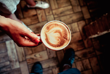 girl holds a cup of cappuccino in hand 3