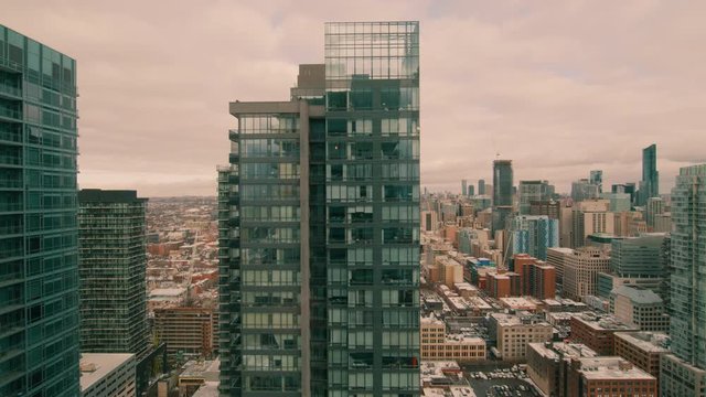 Looking out a high-rise apartment building. The camera tilts down revealing that it is inside an apartment, behind a window. People and cars travel below. 