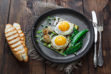 Fried sunny side egg with onion and snow peas, breakfast concept, dark photo copy space