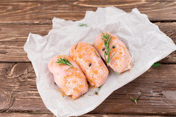 Raw meat, ready for grill or barbeque chicken breast filet, with olive oil, herbs and spices on grey stone background, copy space top view