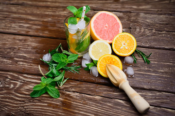 Lemonade with citrus, rosemary and ice on a wooden table. Summer concept.