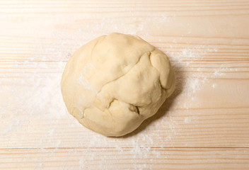 Homemade dough with flour on wooden background. Dough on the background with a place for copispeysa. Homemade cakes, bread, dumplings, dumplings. Home kitchen.
