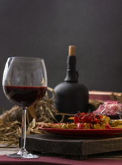 Glass and bottle of wine, cheese and prosciutto on wooden background. Still life