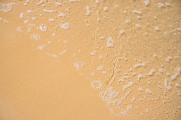 Foamy sea water over yellow sand beach. Tropical seaside concept photo. Seawater on sand beach.