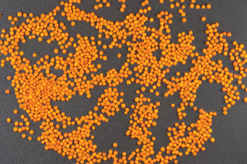 orange lentils on grey background / lentil grains scattered on textured background