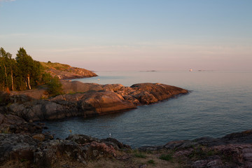 The rocky shore of the island of Suomenlinna and the sea view in the Gulf of Finland at sunset on a summer evening in Finland.