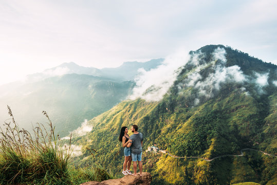 The couple greets the sunrise in the mountains. Boy and girl in the mountains. Man and woman hugging. The couple travels around Asia. Travel to Sri Lanka. Serpentine in the mountains. Honeymoon