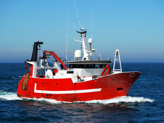 Red fishing boat underway at sea to fishing grounds.