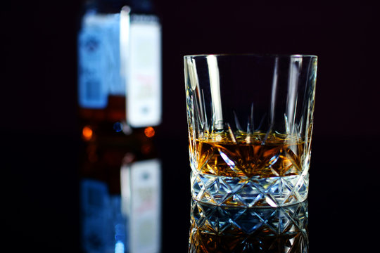 Whiskey In Crystal Glass. Bottle On Background.