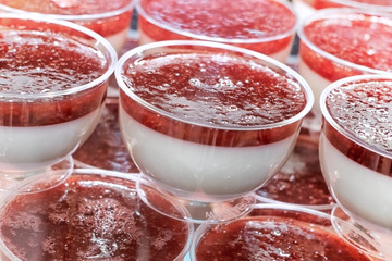 Dessert pudding with strawberry jam in plastic sockets on the counter