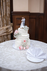 Obraz na płótnie Canvas Beautiful wedding cake with bride and groom cake topper and floral decoration