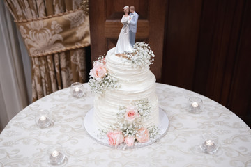 Beautiful wedding cake with bride and groom cake topper and floral decoration