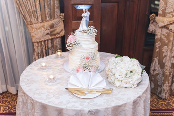 Beautiful wedding cake with bride and groom cake topper and floral decoration