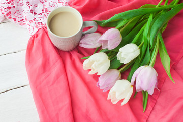 Bouquet of tulips with a mug of coffee and a gift in a red box on a pink cloth. International Women's Day, Valentine's Day, Mother's Day. Selective focus.