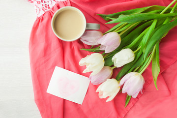 Fototapeta na wymiar Bouquet of tulips with a mug of coffee and a gift in a red box on a pink cloth. International Women's Day, Valentine's Day, Mother's Day. Selective focus.