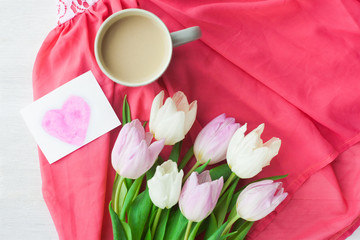 Bouquet of tulips with a mug of coffee and a gift in a red box on a pink cloth. International Women's Day, Valentine's Day, Mother's Day. Selective focus.