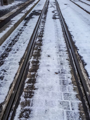 Fototapeta premium Pedestrian and railroad covered with snow in winter. Slippery cobble stones.