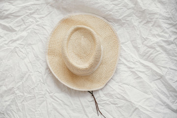 Fototapeta na wymiar Stylish straw hat on white sheets flat lay with copy space. International Women's Day. Summer vacation concept. Travel time. Sun protection