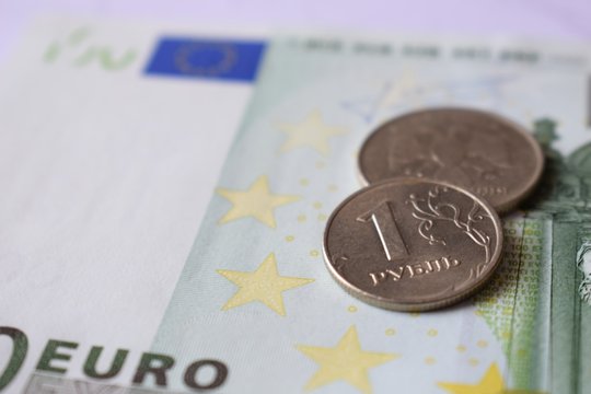 Russian metal coin 1 ruble closeup on the background of the European banknote 