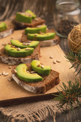 bruschetta with chopped avocado, olive oil, and seeds of seeds and sesame. Healthy vegetarian breakfast on wooden background, healthy nutrition and healthy food.