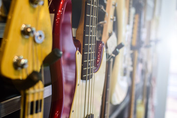Guitars and bass guitar hanging on the wall at a store. Back lights.
