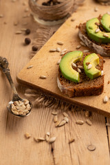 bruschetta on a wooden background with avocado and seeds of shooting, olive oil. Background for design, healthy and clean nutrition. Vegan food