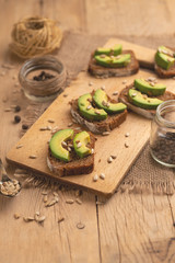 bruschetta on a wooden background with avocado and seeds of shooting, olive oil. Background for design, healthy and clean nutrition. Vegan food