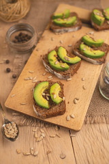 bruschetta on a wooden background with avocado and seeds of shooting, olive oil. Background for design, healthy and clean nutrition. Vegan food