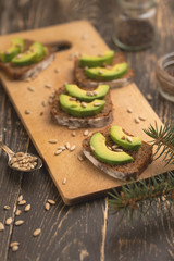 ciabatta toasts, bruschetta with chopped avocado, olive oil, and seeds of sesame and sesame. Healthy vegetarian breakfast on wooden background