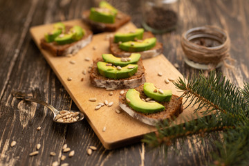 ciabatta toasts, bruschetta with chopped avocado, olive oil, and seeds of sesame and sesame. Healthy vegetarian breakfast on wooden background