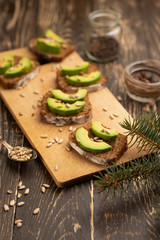 bruschetta with chopped avocado, olive oil, and seeds of seeds and sesame. Background for design. Healthy vegetarian breakfast on wooden background, healthy nutrition and healthy food.