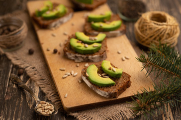bruschetta with chopped avocado, olive oil, and seeds of seeds and sesame. Healthy vegetarian breakfast on wooden background, healthy nutrition and healthy food.